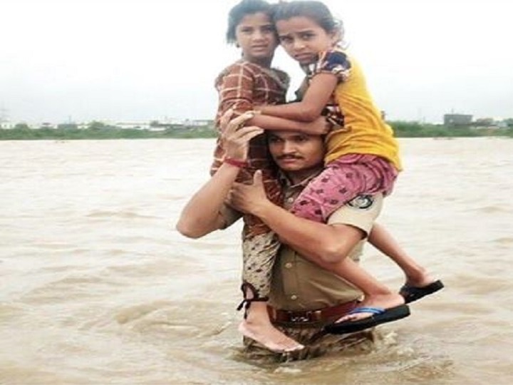 Gujarat Cop Carries 2 Kids On Shoulders In Flood Water, Earns Praise Salute! Gujarat Cop Carries 2 Kids On Shoulders In Flood Water, Earns Praise; Watch Video