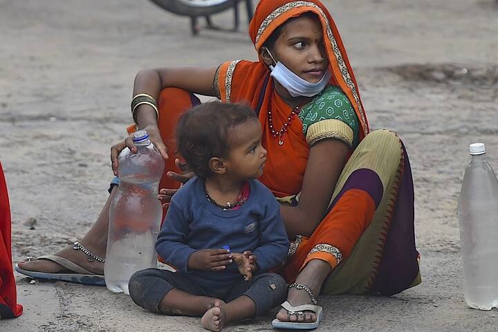 A migrant worker sits on the ground with her child, taking a small break from what will be a long travel ahead. (Photo Credit: AFP)