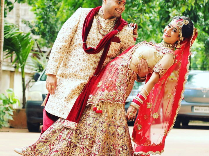 Indian couple posing for maternity baby shoot. The couple is posing in a  lawn with green grass and the woman is falunting her baby bump in Lodhi  Garden in New Delhi, India