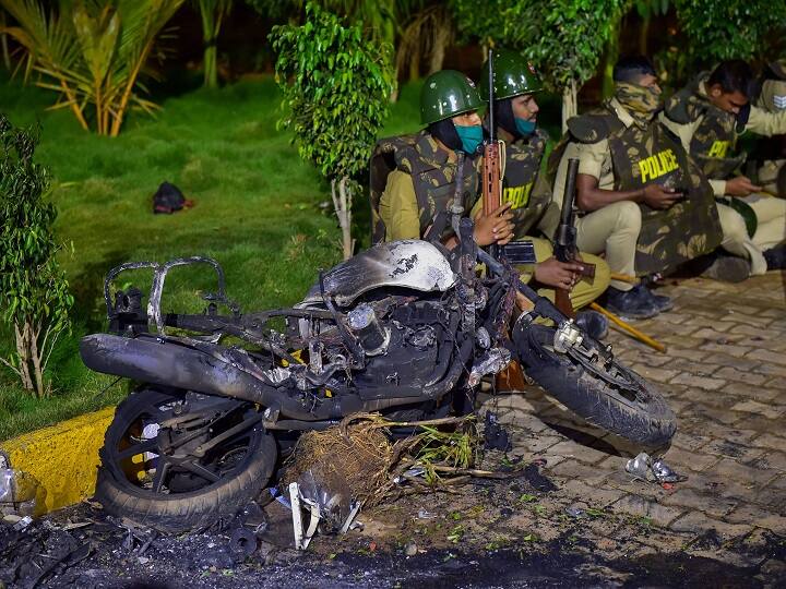 Bengaluru: Police stand next to the charred remains of a vehicle vandalised by a mob over a social media post by a relative of a MLA, in Bengaluru, Wednesday morning, Aug. 12, 2020. (PTI Photo/Shailendra Bhojak)(PTI12-08-2020_000028B)