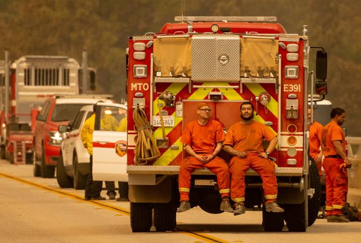Firefighters sit on the back of a fire truck on the Enterprise Bridge during the Bear fire, part of the North Lightning Complex fires, in unincorporated Butte County, in Oroville, California. The Butte County has been the most affected by the Bear fire. Three people have also lost their lives due to the fire.Image (AFP)