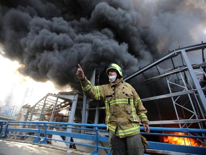A fireman points to his comrades as he stands in front of smoke billowing from a huge fire that raged in Beirut's port on September 10, 2020. (Photo by ANWAR AMRO / AFP)
