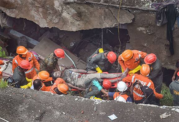 National Disaster Response Force (NDRF) and fire brigade rescue an injured person from the rubble. In a report by PTI a civic official said that the building, situated at Patel compound of Narpoli near Dhamankar Naka, collapsed at 3.40 AM, while the residents were asleep. It is being said that around 21 flats collapsed. Image (PTI)