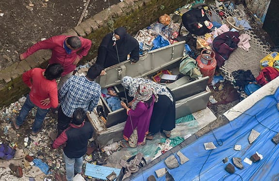 Survivors salvage their belongings from the site. A child was pulled alive by the NDRF in the morning and According to reports, 30-35 people are still trapped under the rubble. Image (PTI)