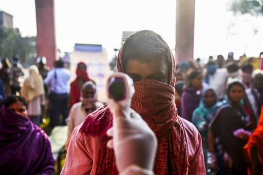 An electoral official checks body temperature of a voter at a polling station in Patna. round 7 lakh hand sanitizers, 46 lakh masks and 6 lakh face shields have been arranged for voters. Image (AFP)