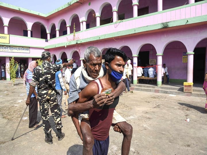 Patna: A young man carrying his father leaves after they cast their votes for the first phase of Bihar Assembly Elections, at Paliganj constituency in Patna, Wednesday,  Oct. 28, 2020. (PTI Photo)