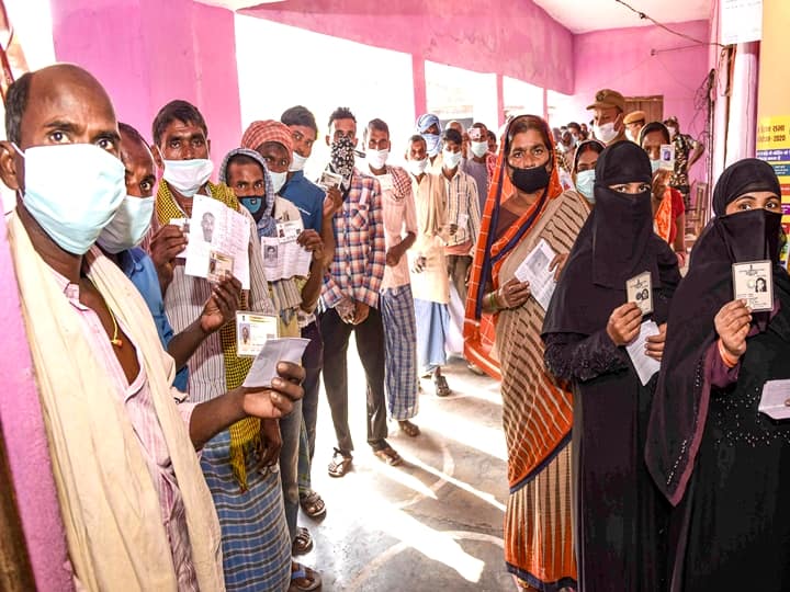 Patna: Voters show their identity cards as they stand in queues at a polling station to cast their votes for the first phase Bihar Assembly Elections, at Paliganj in Patna, Wednesday, Oct. 28, 2020. (PTI Photo)