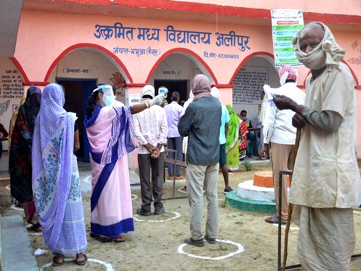Kaimur: Voters undergo thermal screening at a polling booth as they stand in queues to cast their votes for the first phase of Bihar Assembly Election, amid the coronavirus pandemic, in Kaimur district, Wednesday, Oct. 28, 2020. (PTI Photo)