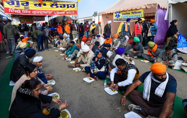 Farmers eat their meal while sitting on road amid a prevailing cold wave in Delhi. (Image Source: PTI)