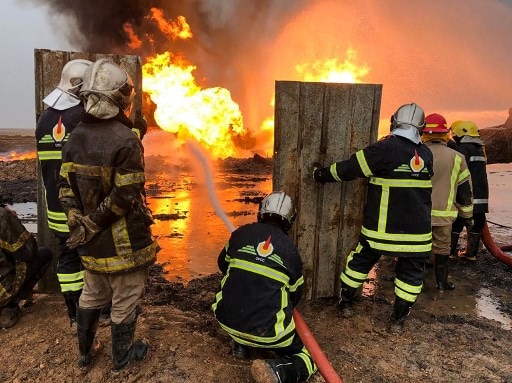Here, firefighters from the Iraqi state-owned North Oil Company put out a fire at an oil well in the northern Khabbaz oil field, about 20 kilometres (12 miles) southwest of Kirkuk in northern Iraq on December 16, 2020. - Iraqi authorities had blamed the Islamic State group (IS) for the fires which had been raging for a week. IS has previously set oil fields aflame in Iraq. (Photo by Marwan IBRAHIM / AFP)