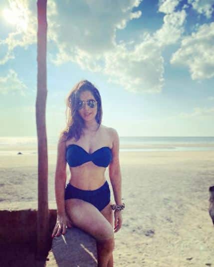 Kim Sharma posing in a stunning black bikini