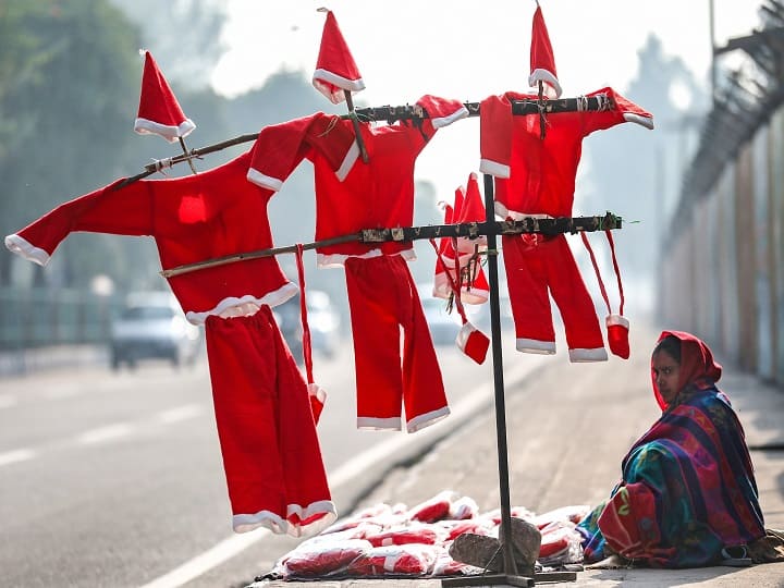 A roadside vendor waits for customers to sell Santa Claus costumes and masks, ahead of Christmas, in Jammu. (Image: PTI)