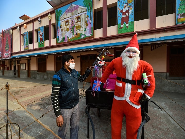 A local administration staff member sanitizes a cart of a man dressed as Santa Claus on the eve of Christmas festival, at Cathridal Church in Lucknow. (Image: PTI)