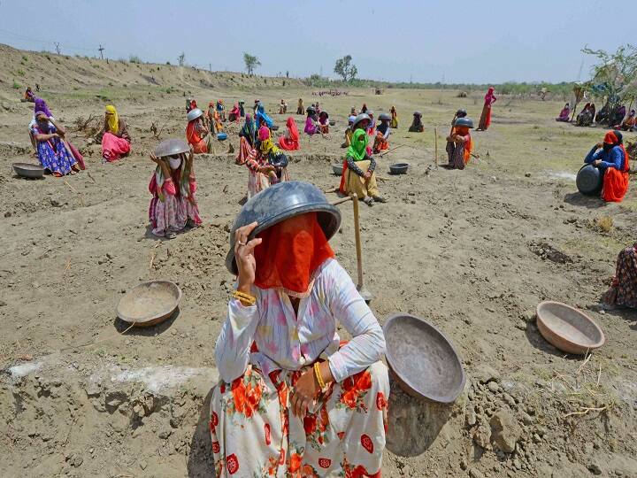Labourers under Mahatma Gandhi National Rural Employment Guarantee Act (MNREGA) sit under tagaris (a pan to carry loads like soil) to protect themselves against the scorching sun, as they work at a site during ongoing COVID-19 lockdown, on the outskirts of Beawar, Friday, May 29, 2020. Rajasthan recorded engagement of over 41.67 lakh labourers in MGNREGA works. (Image: PTI)