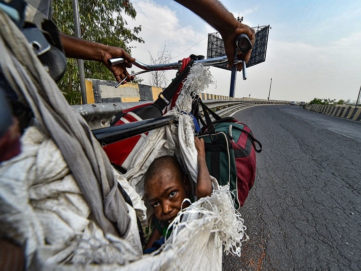A physically challenged girl sits on a makeshift seat of a bicycle as she travels with her family to UP, during the ongoing COVID-19 nationwide lockdown, in New Delhi in May. (Image: PTI)