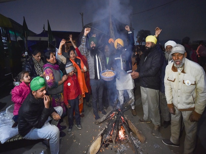 Farmer with their family celebrate Lohri festival during their ongoing protest against the new farm laws ,at Singhu border. (Image: PTI)