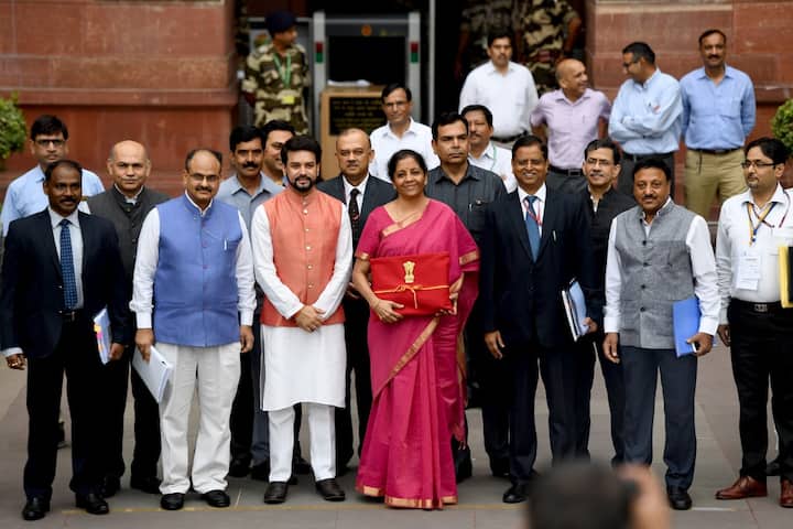 Incumbent Finance Minister Nirmala Sitharaman (C in saree) with Minister of State for Finance Anurag Thakur (3L) looks on as she poses for a picture with her staff before leaving the Indian Finance Ministry for Parliament House to table the General Budget 2019-20 in New Delhi. (File Photo/ AFP)