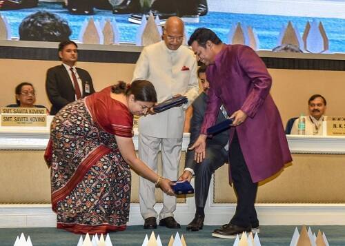 अवॉर्ड संभालने के लिए स्टेज पर झुकीं केन्द्रीय मंत्री स्मृति ईरानी. साथ ही अवॉर्ड संभालते राज्यवर्धन सिंह राठौर और एआर रहमान.