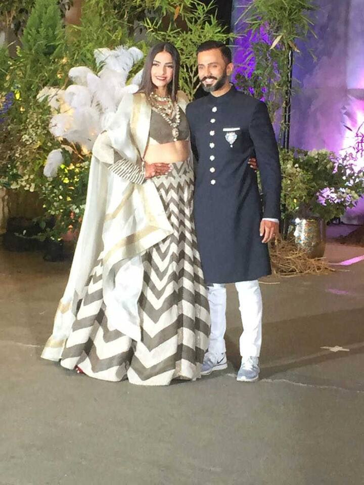 अपने रिसेप्शन पर सोनम कपूर ग्रे और सफेद रंग का लहंगा पहना है, वहीं आनंद ने काले रंग की शेरवानी पहनी है. (तस्वीर: मानव मंगलानी)