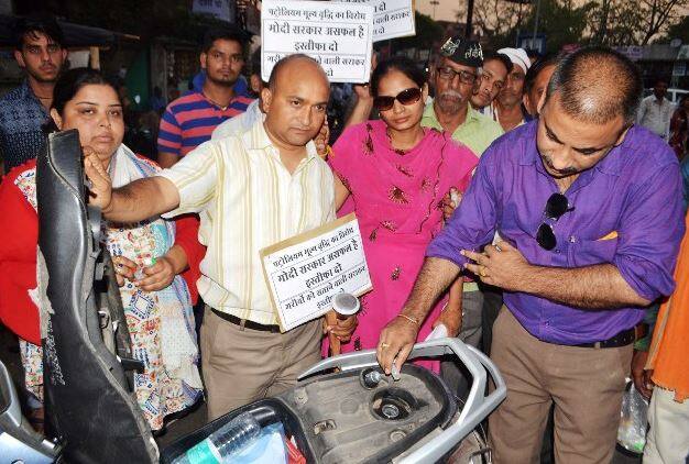 झांसी: झांसी में लोगों ने पेट्रोल-डीजल की बढ़ती कीमतों के खिलाफ अनोखा प्रदर्शन किया. इलाइट चौराहे पर प्रदर्शन के दौरान होम्योपैथिक की बोतल में लोगों को पेट्रोल भेंट किया गया. शहर के सबसे व्यवस्त इलाइट चौराहे पर कुछ युवक युवतियां और बुजुर्ग जेब्रा लाइन के पास खड़े होकर लोगों से विनती कर रहे थे कि मोदी दोबारा आए तो यही होगा. पेट्रोल की बढ़ती कीमत से आने वाले दिनों में पेट्रोल लीटर में नहीं बल्कि मिली लीटर में खरीदना पड़ेगा.