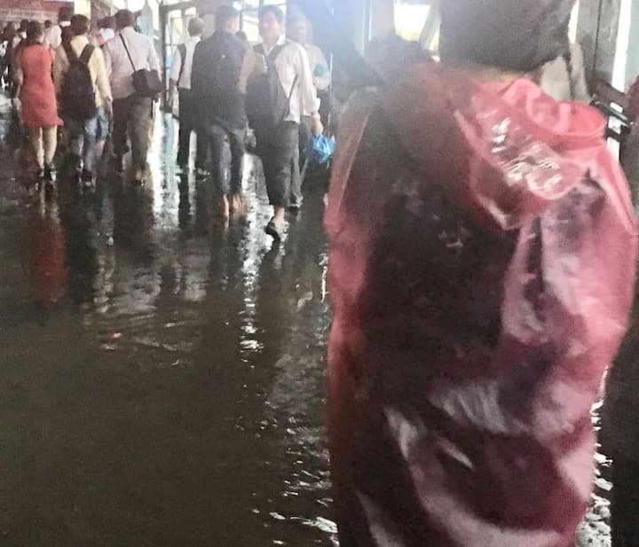 कुरला स्टेशन पर भरे पानी के कारण लोग फुटओवर ब्रिज से जाते दिख रहे हैं. (तस्वीर: एएनआई) 