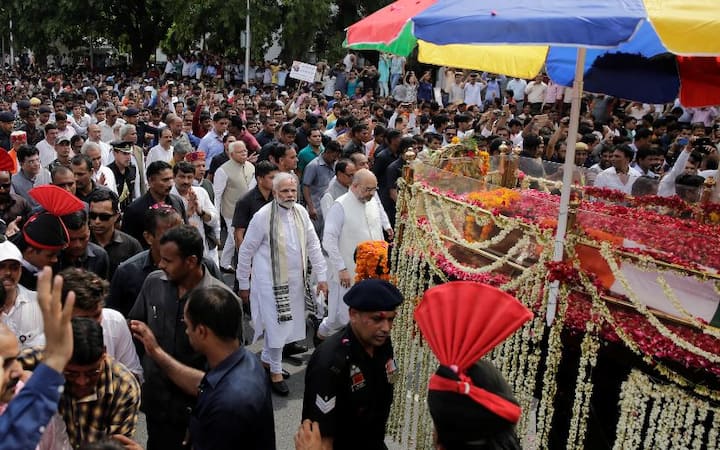 पूर्व प्रधानमंत्री का शव फूलों से सजी तोपगाड़ी में रखा था और हजारों लोग उसके पीछे-पीछे चल रहे थे. इनमें से कुछ धीरे-धीरे चल रहे थे तो कुछ दौड़ रहे थे. प्रधानमंत्री नरेंद्र मोदी और भाजपा अध्यक्ष अमित शाह भी तोपगाड़ी के साथ-साथ पैदल चल रहे थे.