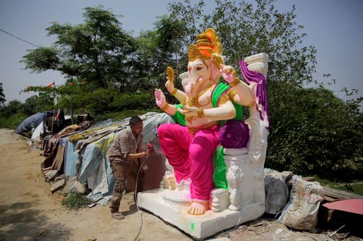 तस्वीर में मूर्तिकार बप्पा की मूर्ति पर रंग लगाता दिख रहा है. फोटोः एपी