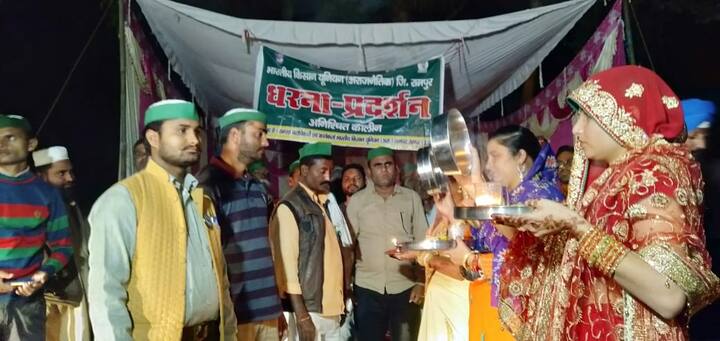 करवा चौथ पर उत्तर प्रदेश के रामपुर में एक अनोखा नजारा देखने को मिला. जब किसानों की पत्नियां व्रत खोलने के लिए धरना स्थल पर पहुंच गईं. दरअसल गन्ने की बकाया पेमेंट और बंद पड़ी चीनी मिलों को खुलवाने की मांग को लेकर किसान पिछले चार-पांच दिन से कलेक्ट्रेट परिसर में धरना प्रदर्शन कर रहे हैं. करवाचौथ के दिन व्रत खोलने के लिए पत्नियों ने भी धरना स्थल का रुख किया और विधि-विधान से व्रत खोला.