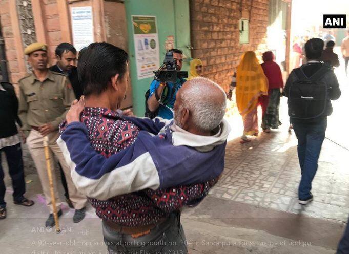 देखिए तस्वीरों में 90 साल के पुरुष को मतदान दिलाने के लिए गोद में उठाकर ले जाते हुए. फोटोः ट्विटर ANI