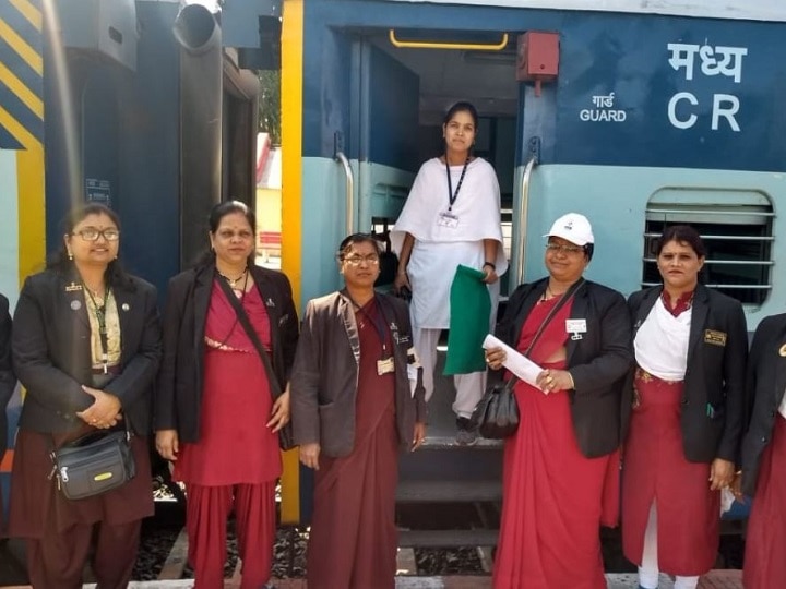 A realistic Indian female train loco pilot in uniform, standing near a railway engine looking concerned or distressed, empty railway station background, monsoon sky, subtle highlight on her expression, no toilet around, emphasis on loneliness and struggle, photojournalism style, cinematic lighting, 16:9 aspect ratio, high resolution.
Text on image: "इंजन में नहीं है वॉशरूम!"