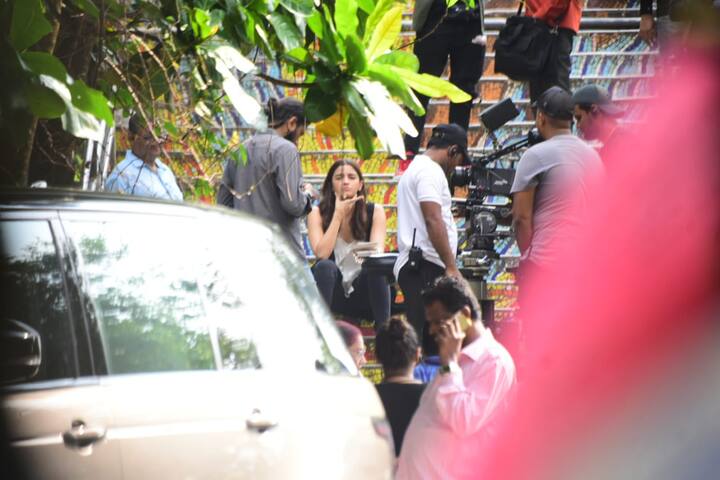 तस्वीरों में आलिया भट्ट चुपचाप अकेली बैठी नज़र आ रही हैं, जबकि फिल्म के सेट पर काफी गहमा गहमी देखी जा सकती है. (तस्वीर: मानव मंगलानी)