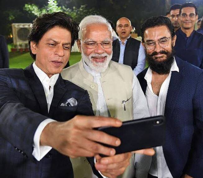 इस इवेंट से सामने आई तस्वीरें सोशल मीडिया पर खूब वायरल हो रही हैं. इस दौरान आमिर खान और शाहरुख खान पीएम मोदी के साथ खूब सेल्फियां लेते दिखाई दिए. (Photo Credit: @manav.manglani Instagram)