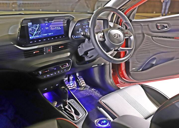 इसका केबिन अपने आप में स्पोर्टी है जिसमें टर्बो वर्जन है जिसमें रेड कलर के साथ ऑल ब्लैक इंटीरियर है. बटन क्वालिटी में अच्छे हैं, लेकिन डैश पर अधिक सॉफ्ट टच मेटेरियल मिलेगा. इसमें कई ऐसे फीचर्स दिए गए हैं जो आम तौर पर हैचबैक कारों में नहीं मिलते हैं जैसे वायरलेस चार्जिंग, एयर प्यूरीफायर, इलेक्ट्रिक सनरूफ, बोस 7 स्पीकर ऑडियो और कनेक्टेड टेक जहां आपको ओटीए मैप अपडेट मिलते हैं. आप इसमें एक से ज्यादा ब्लूटूथ डिवाइस भी जोड़ सकते हैं. बेशक इसमें रियर एसी वेंट जैसे यूजुअल फीचर्स दिए गए हैं. हमनें कहा है कि वेन्यू या वेर्ना दोनों में रियर सीट की कमी है लेकिन नए i20 में इसका ध्यान रखा गया है. चौड़ाई और लंबे व्हीलबेस के कारण इसमें तीन बैठ सकते हैं जिसका मतलब है कि यह प्रतिद्वंद्वियों की तुलना में अधिक स्पेशियस और आरामदायक है.