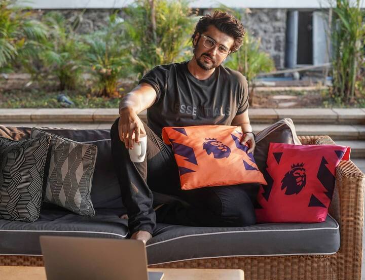 अर्जुन कपूर ने ब्लैक टीशर्ट और ब्लैक पैंट पहनी है और वो इस तस्वीर में सोफे पर बैठकर आराम फरमाते हुए दिखाई दे रहे हैं. उन्होंने हाथ में कॉफी मग पकड़ा हुआ है. (Photo Credit - Instagram)