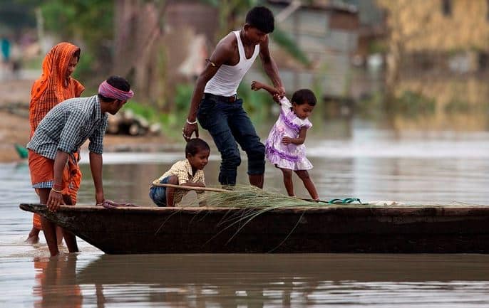 বন্যায় ডুবে গিয়েছে বাড়ি। নিরাপদ আশ্রয়ের খোঁজে নৌকা নিয়ে চলেছে একটি পরিবার।
