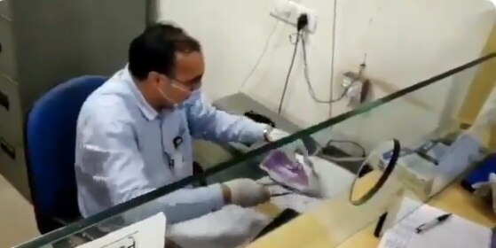 Gujarat banker uses steam iron to disinfect cheque. Anand Mahindra shares viral clip চিমটি দিয়ে ধরে ইস্ত্রিতে সেঁকে চেক জীবাণুমুক্ত করছেন ব্যাঙ্ককর্মী! ভাইরাল ভিডিও