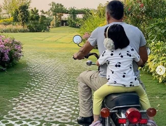 MS Dhoni takes Ziva on a bike ride রাঁচির ফার্মহাউসে জীভাকে বাইকে চাপিয়ে ঘুরলেন ধোনি, ভিডিও শেয়ার করলেন সাক্ষী