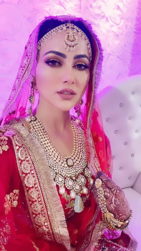 পরনে লাল লেহেঙ্গা, তাক লাগানো ঝলমলে নেকপিস, গা ভর্তি সোনার গয়না। নজর কেড়েছে তাঁর মুক্তোর অলঙ্কারও। কনের সাজে তাঁর মেক-আপ সোশ্যাল মিডিয়ায় চর্চার বিষয়। 