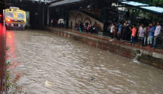 संततधार पावसाचा मुंबईतील लोकल रेल्वे आणि रस्ते वाहतुकीला मोठा फटका बसला आहे. मुंबईतल्या अनेक भागात पाणी साचलं आहे. मध्य रेल्वेच्या सायन स्टेशनजवळ ट्रॅकवर पाणी साचलं आहे. यामुळे रेल्वे वाहतुकीचा खोळंबा झाला आहे. तर अंधेरी स्टेशनवर विलेपार्ले एंडच्या बाजूने प्लॅटफॉर्म क्र. 8 आणि 9 च्या दरम्यान पुलाचा फुटपाथ कोसळल्यामुळे रेल्वेची वाहतूक ठप्प झाली आहे. 
