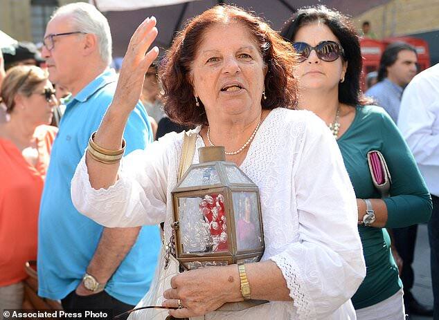 A woman holds a container with a candle and a photo of the slain journalist Daphne Caruana Galizia, during a demonstration in front of Valletta's Law Courts, Malta, Tuesday Oct. 17, 2017. The Maltese investigative journalist who exposed the island nation's links to offshore tax havens through the leaked Panama Papers was killed Monday when a bomb exploded in her car. (AP Photo/ Rene Rossignaud)