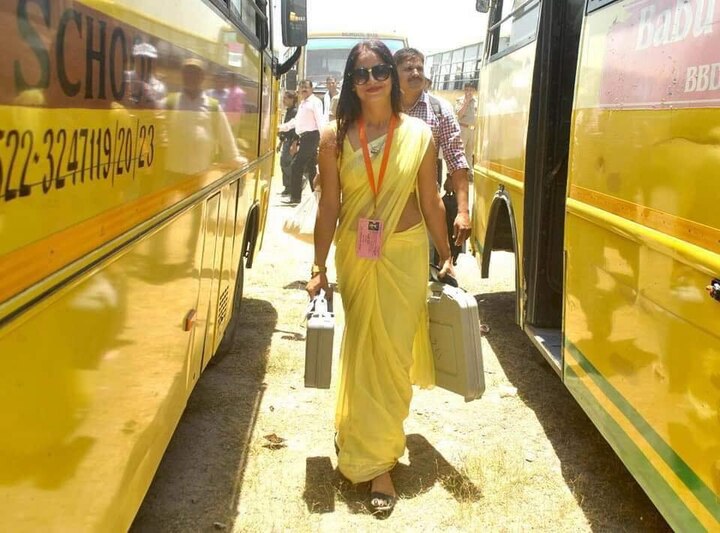 lady polling officer in yellow saree 100 percent voting percentage EVM મશીન લઈને જતી બ્યુટીફુલ મહિલા અધિકારીએ સોશિયલ મીડિયા પર મચાવી ધૂમ, જાણો કોણ છે આ યુવતી?